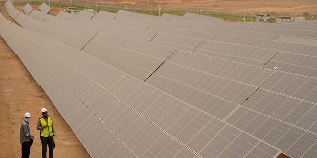 Engineers talk next to photovoltaic solar panels at the Benban Solar Park, one of the world's largest solar power plants, in Aswan, Egypt, October 3.  19, 2022.