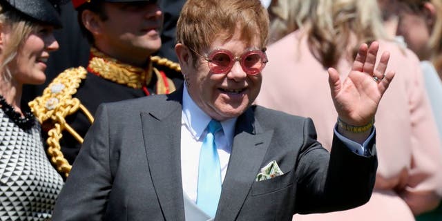 Elton John waves as he leaves the wedding ceremony of Prince Harry and Meghan Markle at St. George's Chapel at Windsor Castle on May 19, 2018.