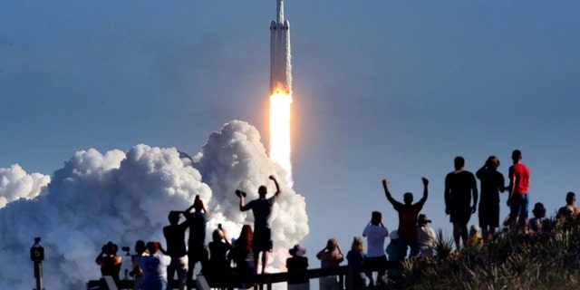 The crowd cheers at Playalinda Beach in the Canaveral National Seashore, just north of the Kennedy Space Center, during the launch of the SpaceX Falcon Heavy rocket, on Feb. 6, 2018. 