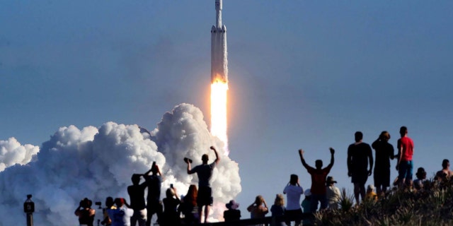The crowd cheers at Playalinda Beach in the Canaveral National Seashore, just north of the Kennedy Space Center, during the launch of the SpaceX Falcon Heavy rocket, on Feb. 6, 2018.