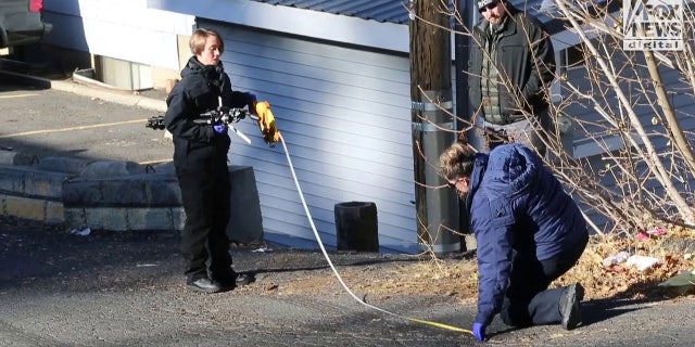 A forensics team returned to the street in front of the crime scene to measure tire marks.