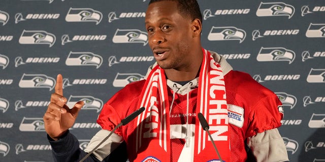 Seattle Seahawks quarterback Geno Smith wears an FC Bayern Munich scarf as he answers questions during a news conference after a practice session in Munich, Germany, Thursday, Nov. 10, 2022.