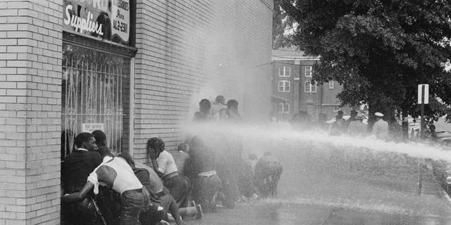 Os bombeiros usam mangueiras de incêndio para subjugar os manifestantes durante a campanha de Birmingham em Birmingham, Alabama, em maio de 1963. O movimento, que pedia a integração dos afro-americanos nas escolas, foi organizado por Martin Luther King Jr. e Fred Shuttlesworth, entre outros.  