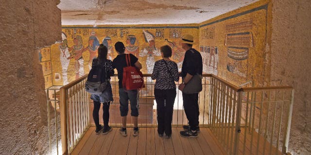 A group of tourists take a look at Pharaoh Tutankhamun's golden sarcophagus, which is on display in the burial chamber of his underground tomb (KV62) in the Valley of the Kings.