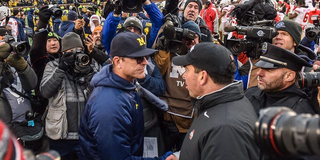 Head coach Ryan Day of the Ohio State Buckeyes, right, shakes hands with head coach Jim Harbaugh of the Michigan Wolverines after a game at Michigan Stadium Nov. 30, 2019, in Ann Arbor, Mich. The Ohio State Buckeyes won the game 56-27. 