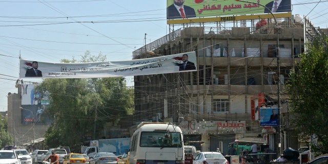 Iraqis walk past election posters and candidate banners in the Karrada district of the capital Baghdad.