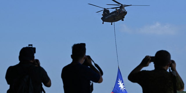 A US-made CH-47 helicopter flies an 18-meter by 12-meter national flag at a military base in Taoyuan. 