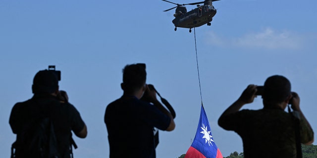 A US-made CH-47 helicopter flies an 18-meter by 12-meter national flag at a military base in Taoyuan.