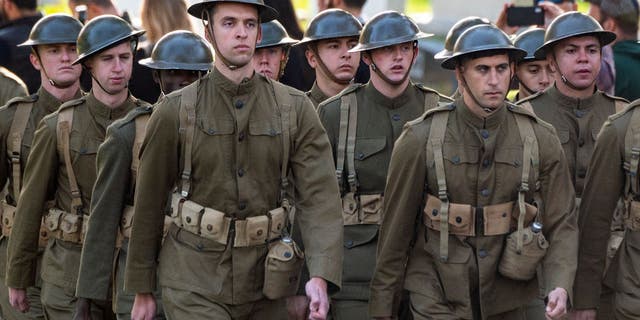 U.S. troops march during a joint full honors procession evoking the original 1921 funeral procession of a World War I unknown soldier, in commemoration of the 100th anniversary of the Tomb of the Unknown Soldier on Veterans Day in Arlington National Cemetery on Nov. 11, 2021 in Arlington, Virginia.