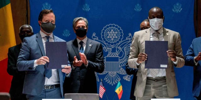 U.S. Secretary of State Antony Blinken (background L) applauds as ABD Group CEO John Nevergole (L) and Ageroute Director General Ibrahima Ndiaye (R) sign an agreement during a commercial diplomatic event with U.S. companies and the government of Senegal at the Radisson Blu Hotel in Dakar, on November 20, 2021.