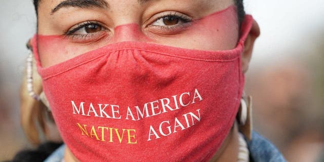 Micah Stasis, wearing a mask with the words "Make America Native Again", looks on during the National Day of Mourning on Thanksgiving Day, Nov. 25, 2021, in Plymouth, Massachusetts.