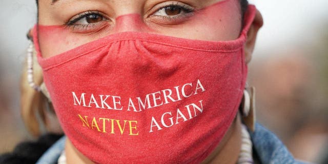 Micah Stasis, wearing a mask with the words "Make America Native Again"is seen during the National Day of Mourning on Thanksgiving Day, November 25, 2021, in Plymouth, Massachusetts.