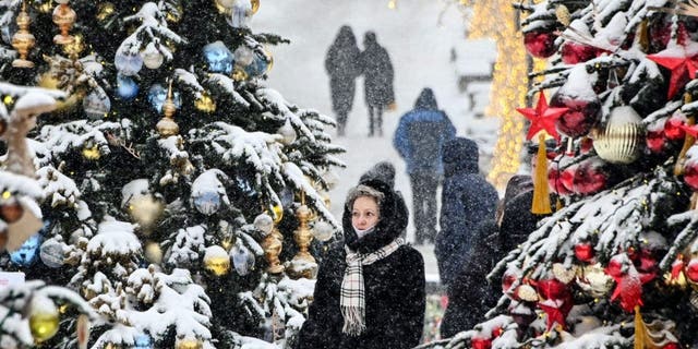 People walk past Christmas and New Year decorations in downtown Moscow, December 25, 2021. 