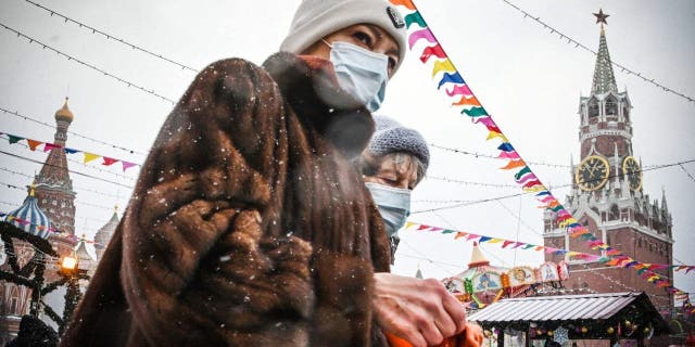 2022. gada 15. janvārī apmeklētāji pastaigājas pa Ziemassvētku un Jaungada tirgu iepretim Kremļa Spasskaya tornim Sarkanajā laukumā Maskavā.