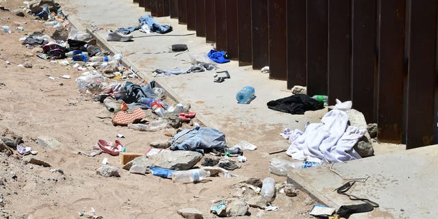 Clothing, shoes, and other debris pile up next to the US-Mexico border wall that separates Algodones, Mexico, from Yuma, Arizona, on May 16, 2022. 