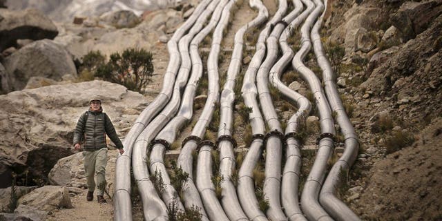 Noa Walker Crawford, a British external consultant on climate change, walks next to pipes as he leaves the Palcacocha Lake, located at 4,650 meters above sea level at the Huascaran National Park, in Huaraz, northeastern Peru, on May 23, 2022.
