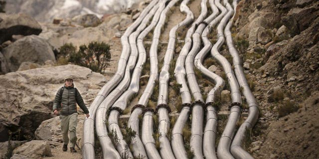 Noa Walker Crawford, British external consultant on climate change, walks beside the pipes as she leaves Lake Palcacocha, located 4,650 meters above sea level in Huascaran National Park, in Huaraz, northeastern Peru, on May 23, 2022.