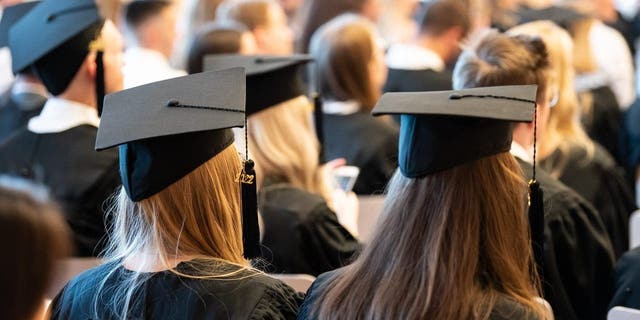 College students stand in their caps and gowns at graduation.