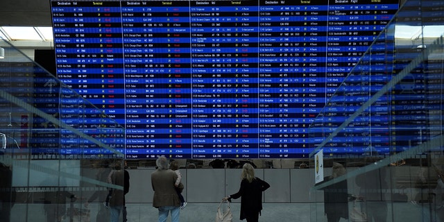 This photograph, taken on September 16, 2022, shows travelers looking at the departure information panel at Roissy-Charles de Gaulle Airport Terminal 2. 