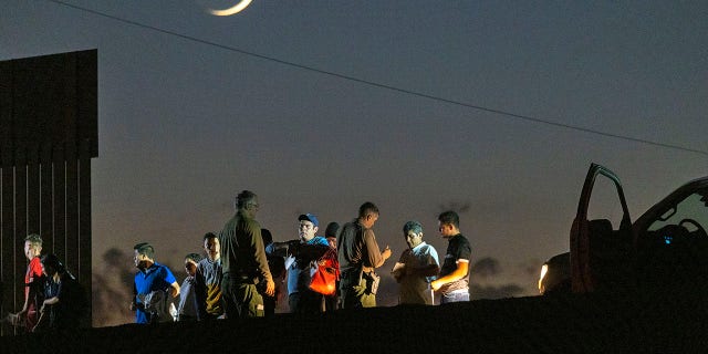Border patrol agents take people into custody next to the U.S.-Mexico border fence where the last of the Colorado River flows into Mexico on September 27, 2022 near Yuma, Arizona.