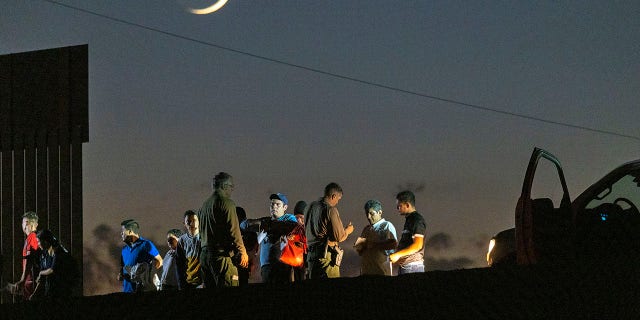 Border patrol agents take people into custody next to the U.S.-Mexico border fence where the last of the Colorado River flows into Mexico on September 27, 2022 near Yuma, Arizona. 