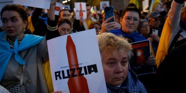 A woman holds a sign with a grahpic of a missile rocket during a rally in front of the Russian Embassy in Warsaw, Poland on 10 October, 2022. 