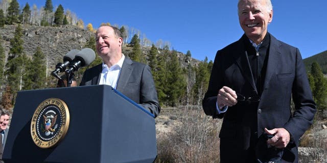 U.S. President Joe Biden (R) smiles as Colorado Gov. Jared Polis delivers remarks about protecting America's iconic outdoor spaces at Camp Hale near Leadville, Colo., on Oct. 12, 2022.