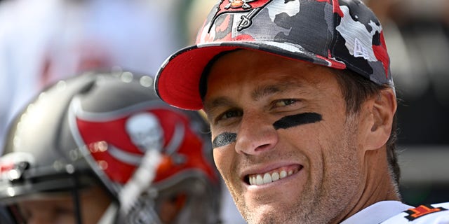 Tom Brady smiles in his camouflage Bucaneer's hat