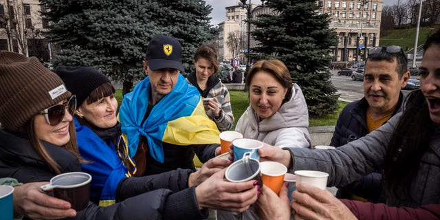 Хората пият пенливо вино, развяват знамена и пеят песни, докато празнуват освобождаването на част от Херсон на Площада на независимостта на 12 ноември 2022 г. в Киев, Украйна. 