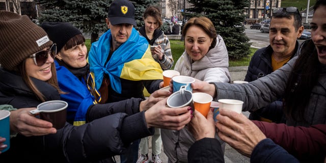 People drink sparkling wine, wave flags and sing songs as they celebrate the liberation of part of the city of Kherson at Independence Square on November 12, 2022 in Kiev, Ukraine. 