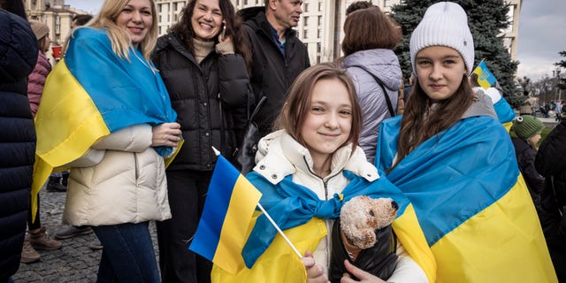 People drink sparkling wine, wave flags and sing songs as they celebrate the liberation of part of the city of Kherson at Independence Square on November 12, 2022 in Kiev, Ukraine. 