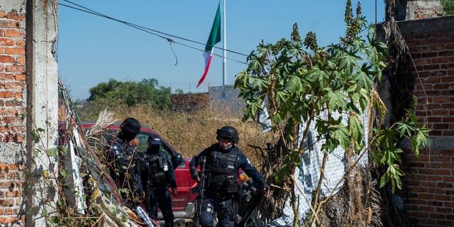 Police officers protect members of the "Hasta Encontrarte" ("Until we find you") collective during the search for missing relatives in a clandestine grave at the Santa Fe neighborhood of Irapuato, Guanajuato state, Mexico, on November 10, 2022.