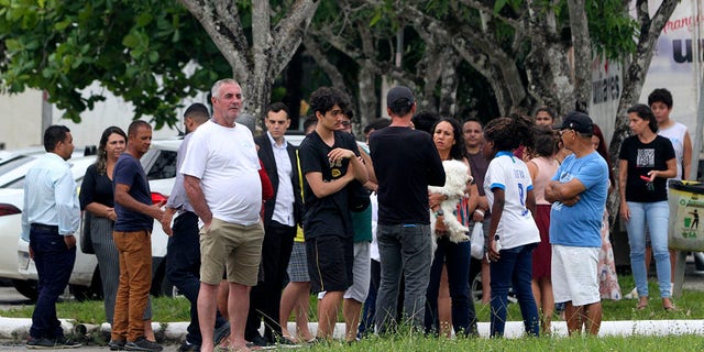 Relatives of pupils stand at the entrance of the Praia de Coqueiral Educational Centre, one of two schools where a shooting took place, after an armed suspect opened fire, in Aracruz, Espirito Santo State, Brazil, on November 25, 2022. 