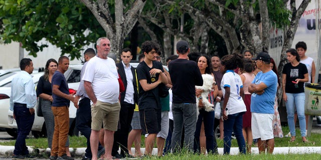 Relatives of students stand at the entrance of the Praia de Coqueiral Education Center, one of two schools where a shooting occurred after an armed suspect opened fire in Aracruz, Espiritu Santo state, Brazil, on November 25, 2022. 