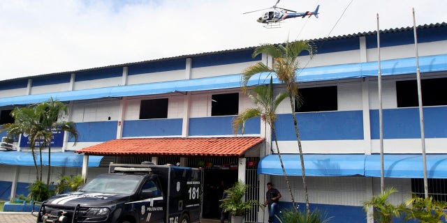 Police officers stand at the entrance of the Primo Bitti State School, one of two schools where a shooting took place, after an armed suspect opened fire, in Aracruz, Espirito Santo State, Brazil, on November 25, 2022. 