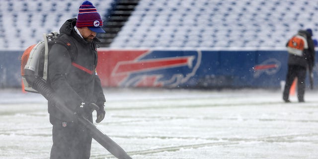 A field crew member uses a blowing machine to move snow on the field prior to the game between the Atlanta Falcons and the Buffalo Bills at Highmark Stadium on Jan. 2, 2022 in Orchard Park, New York. 