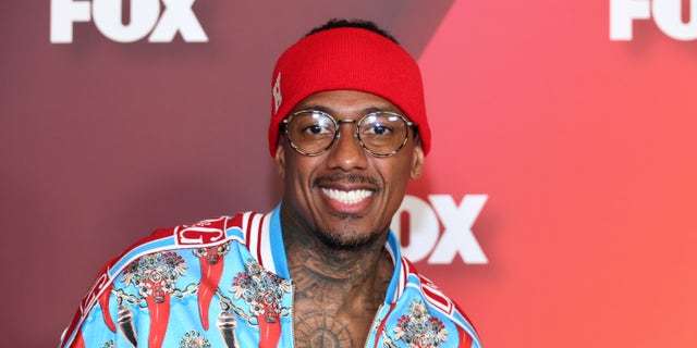 Nick Cannon smiles at the Fox Upfronts, in a red and blue shirt