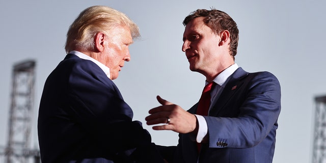 Former President Donald Trump, left, shakes hands with Republican Senate candidate Blake Masters at a campaign event at Legacy Sports USA.