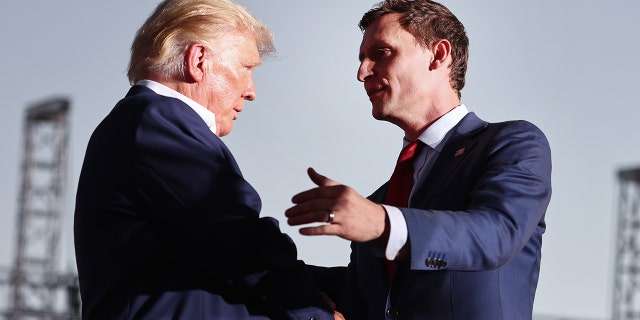 Former US President Donald Trump (L) shakes hands with Republican US Senate candidate Blake Masters at a campaign rally at Legacy Sports USA.