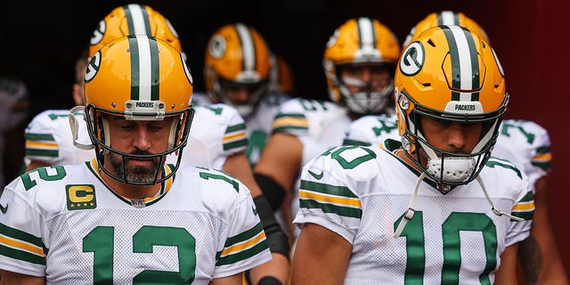 Aaron Rodgers and Jordan Love walk onto the field before the game against the Commanders