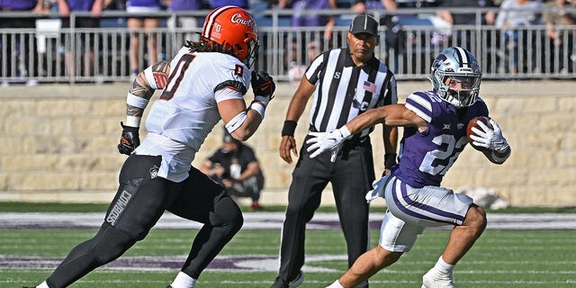 Running back Deuce Vaughn (22) of the Kansas State Wildcats runs to the outside against linebacker Mason Cobb (0) of the Oklahoma State Cowboys during the first half at Bill Snyder Family Football Stadium Oct. 29, 2022, in Manhattan, Kan. 