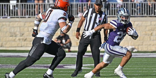 Running back Deuce Vaughn (22) of the Kansas State Wildcats runs to the outside against linebacker Mason Cobb (0) of the Oklahoma State Cowboys during the first half at Bill Snyder Family Football Stadium Oct. 29, 2022, in Manhattan, Kan.