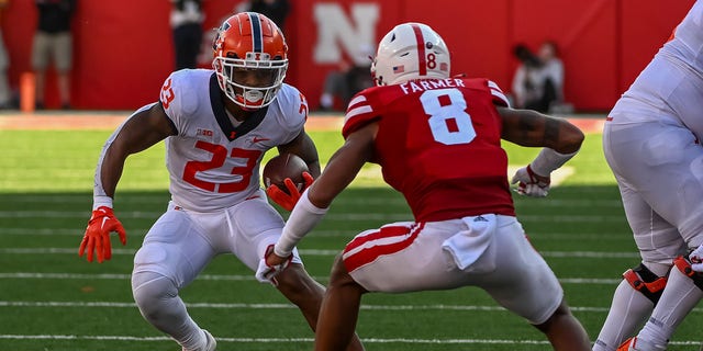 Running back Reggie Love III (23) of the Illinois Fighting Illini attempts to avoid a tackle from defensive back Myles Farmer (8) of the Nebraska Cornhuskers at Memorial Stadium Oct. 29, 2022, in Lincoln, Neb. 