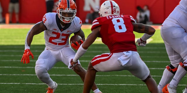 Running back Reggie Love III (23) of the Illinois Fighting Illini attempts to avoid a tackle from defensive back Myles Farmer (8) of the Nebraska Cornhuskers at Memorial Stadium Oct. 29, 2022, in Lincoln, Neb.