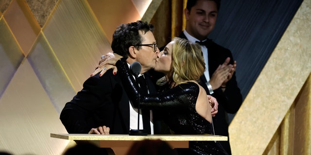 Michael J. Fox is given a kiss on stage from his wife Tracy Pollan after receiving the Jean Hersholt Humanitarian Award.