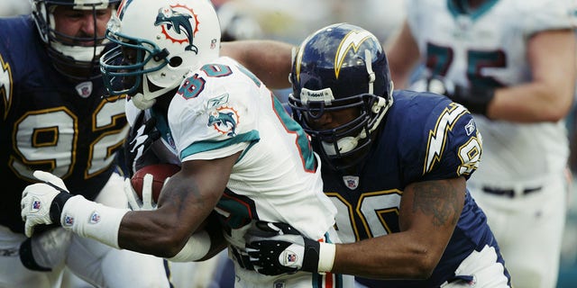 Wide receiver James McKnight of the Miami Dolphins gets tackled by defensive end Adrian Dingle, right, of the San Diego Chargers during the second quarter of a game at Pro Player Stadium in Miami, Florida, on Nov. 24, 2002.