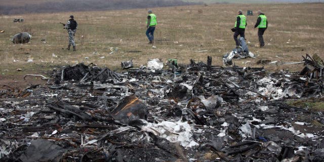 Dutch investigators accompanied by pro-Russian armed rebels arrive near parts of the Malaysia Airlines Flight MH17 at the crash site near the Grabove village in eastern Ukraine on Nov. 11, 2014.