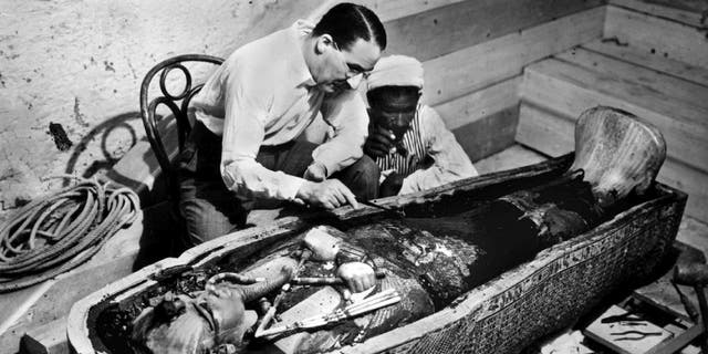 British archeologist and Egyptologist Howard Carter inspects the golden sarcophagus that holds King Tutankhamon's mummy in this 1922 photograph.