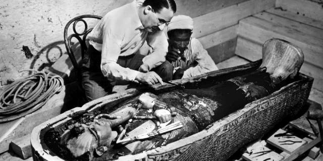 British archeologist and Egyptologist Howard Carter inspects the golden sarcophagus that holds King Tutankhamon's mummy in this 1922 photograph.