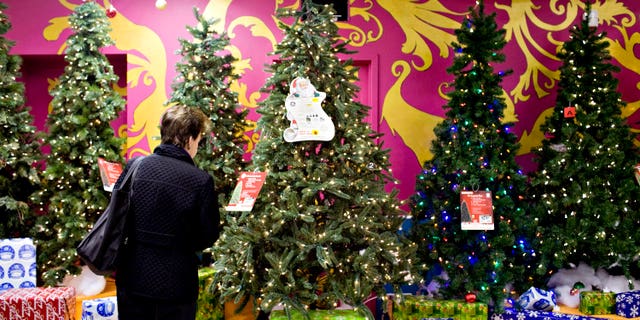 A woman examines an artificial Christmas tree.